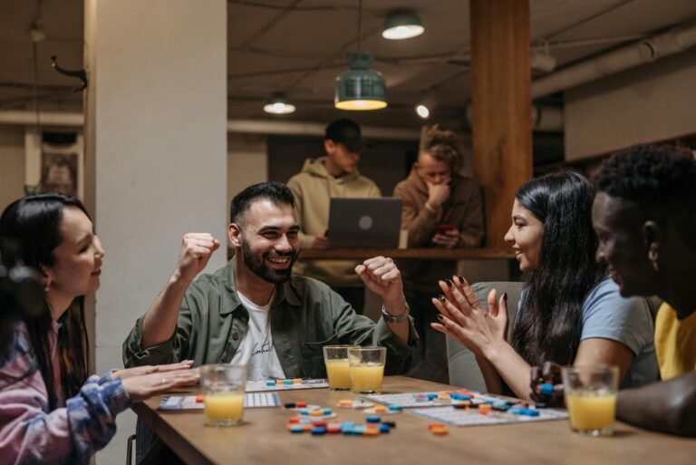 Group of friends playing a board game and laughing at a cozy indoor gathering