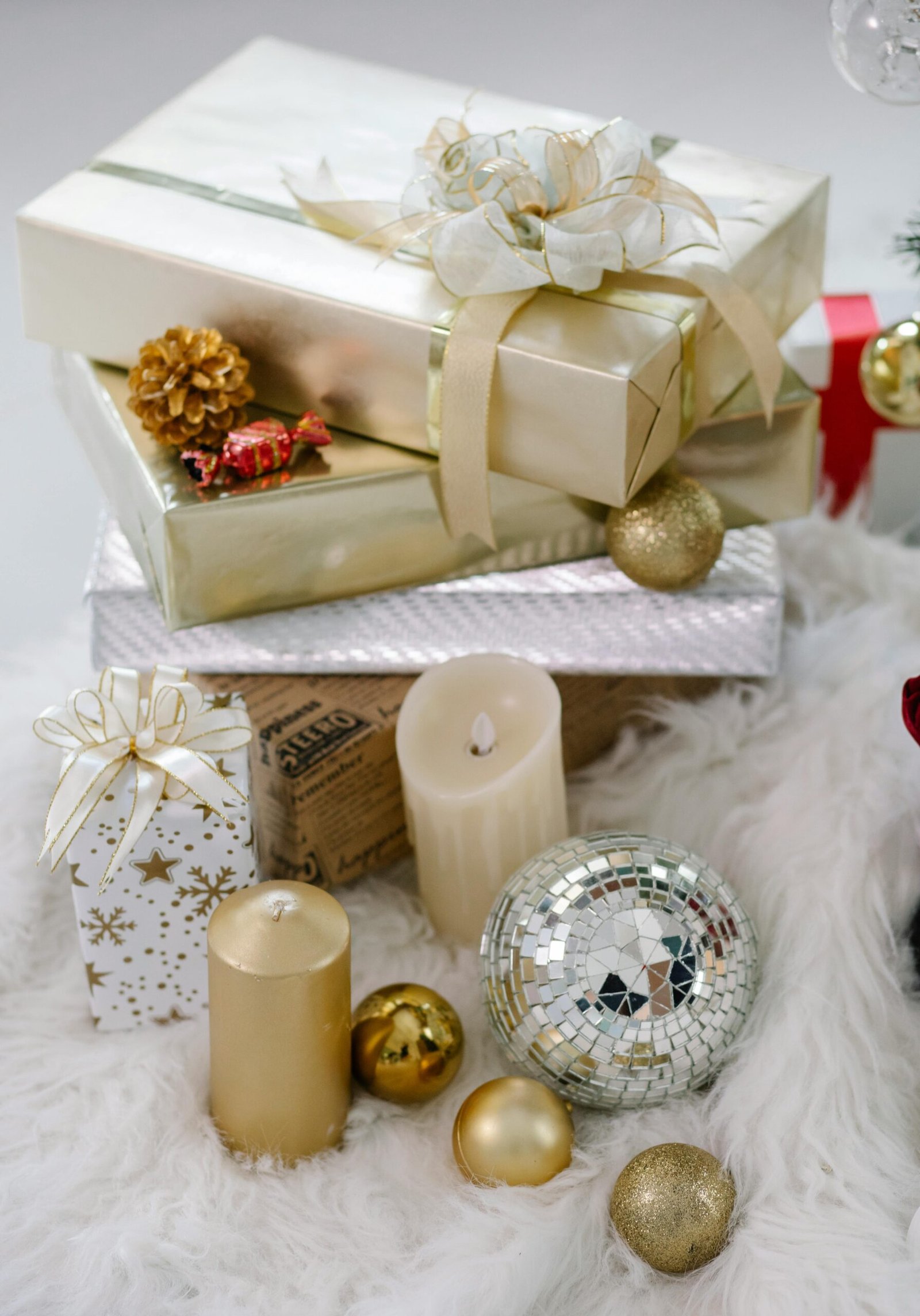 Stack of gold and white Christmas gifts with candles and ornaments